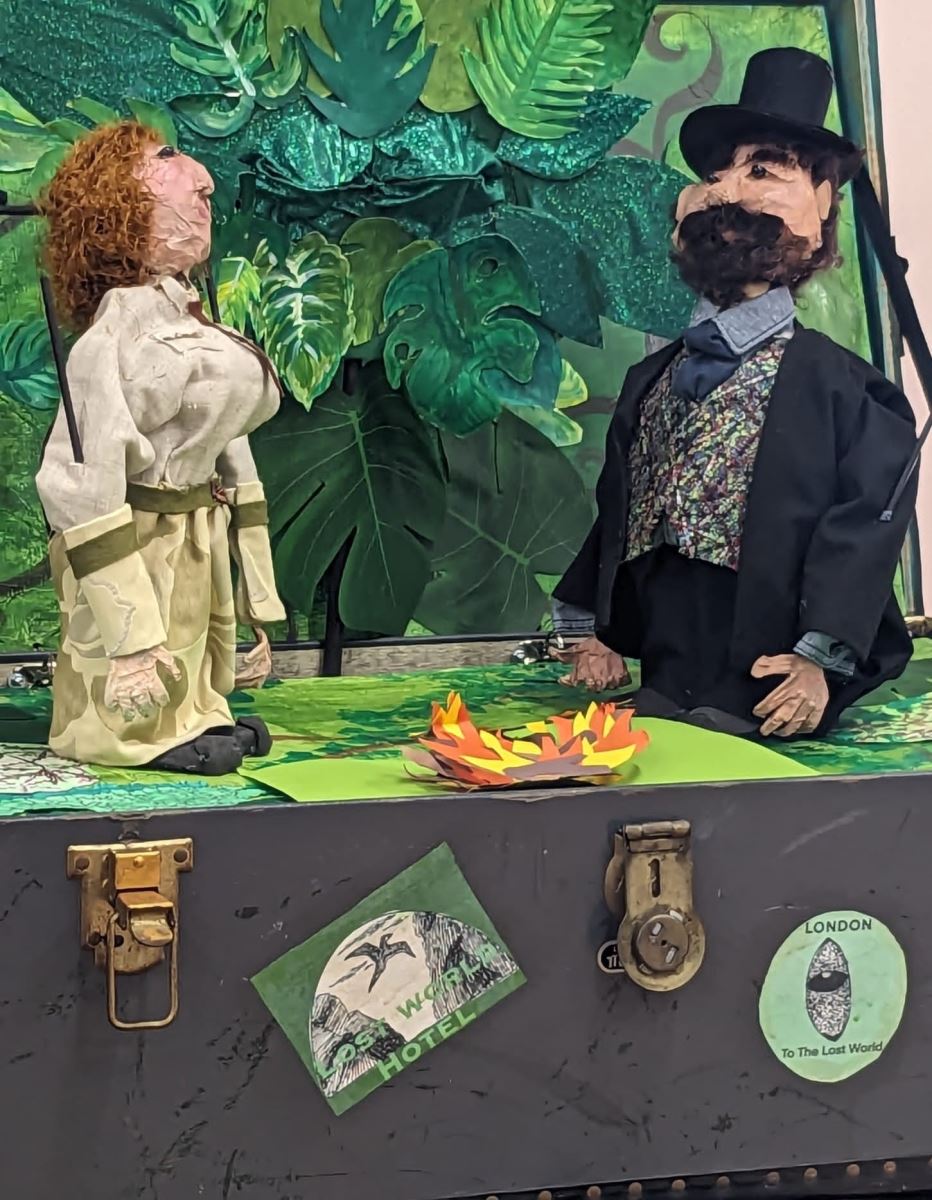 the two human puppets from the previous image facing each other in the jungle